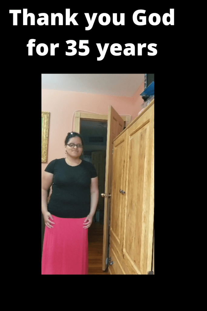 This is a photo of me. I am wearing a short sleeve black shirt with a long coral skirt. I have a black headband with a flower on it. Text on image reads Thank you God for 35 years 