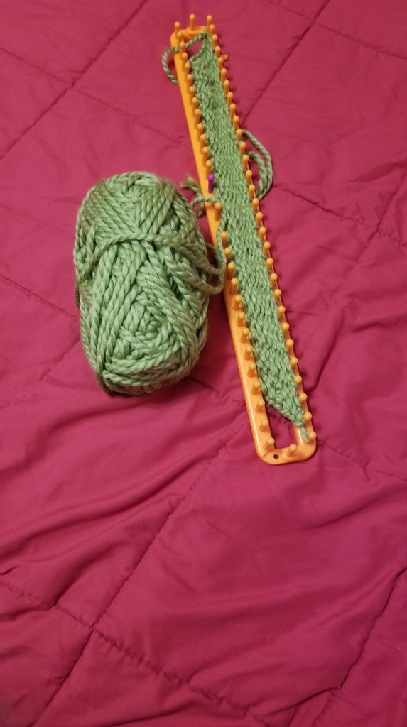 A knitting loom with green yarn attached to it. #hobbies #loomknitting 